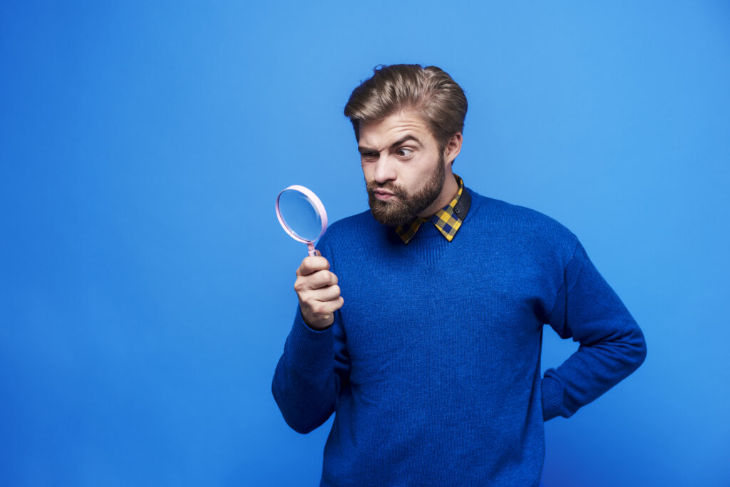 Surprised man looking through a magnifying glass